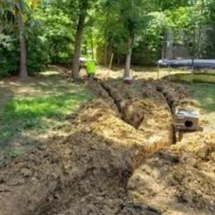 Trench dug across a wooded backyard for a new drainage line