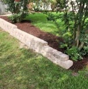 Low tan block wall edging a mulched planting bed beside a lawn