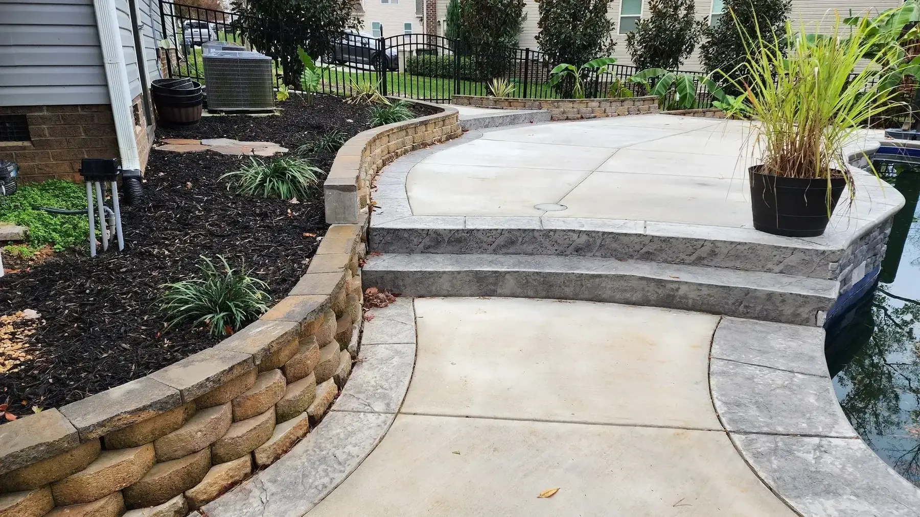 Stone patio with steps and retaining wall, leading to a pool.