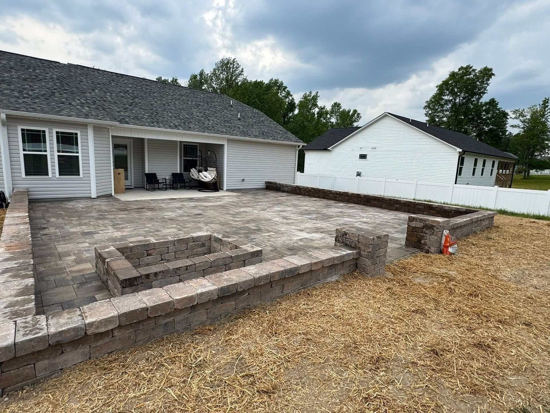 Paver patio with stone seat walls behind a home in the Fuquay-Varina area